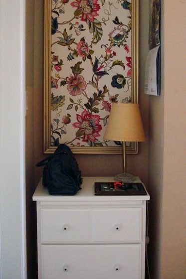 a white dresser sitting next to a wall with a painting on it