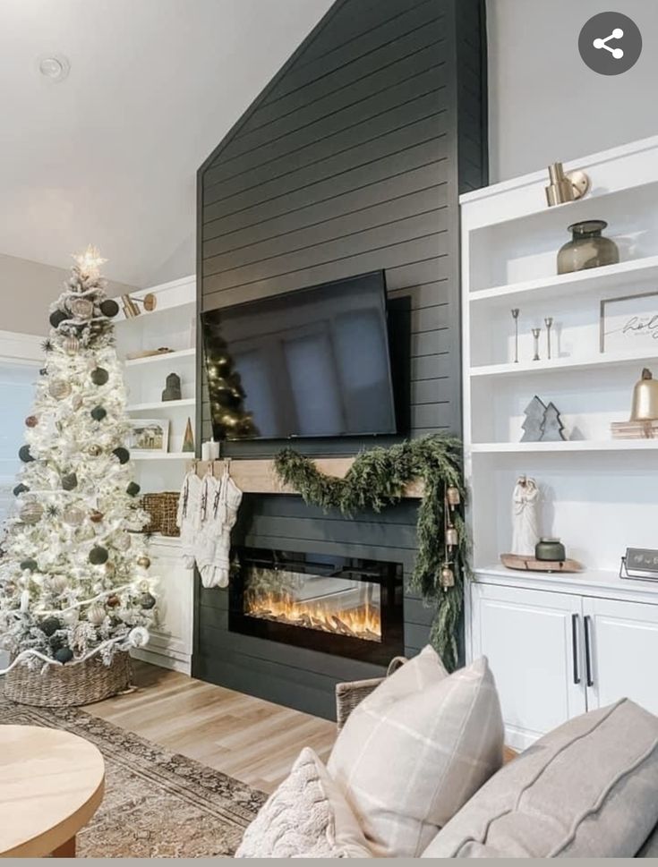 a living room decorated for christmas with a fireplace and tv on the wall above it