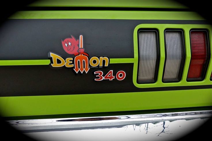 the front end of a green and black car with demon stickers on it