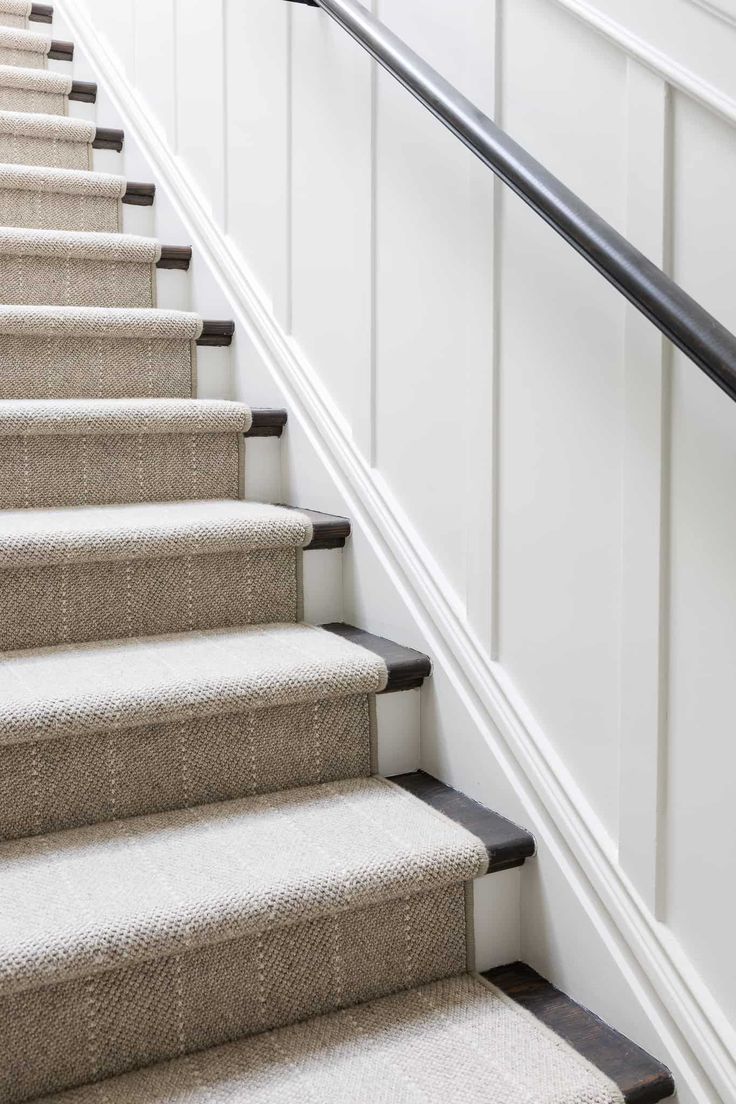 a set of stairs with carpet on the bottom and handrails, leading up to an upstairs landing