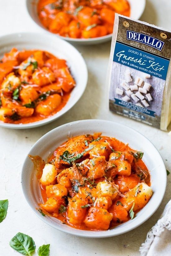 two white bowls filled with food next to a carton of delallo seasoning