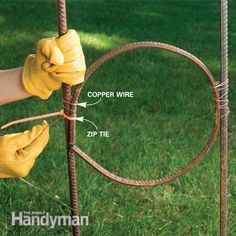 a person in yellow gloves is holding the end of a wire fence with two hands