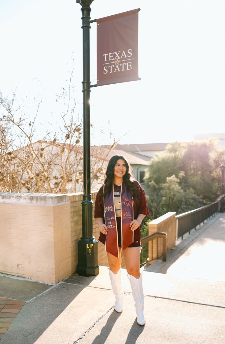 a woman standing under a texas state flag on the side of a street light pole