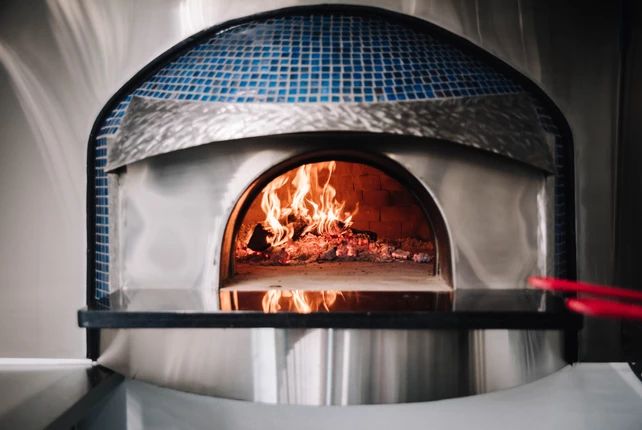 a pizza oven with fire burning inside of it