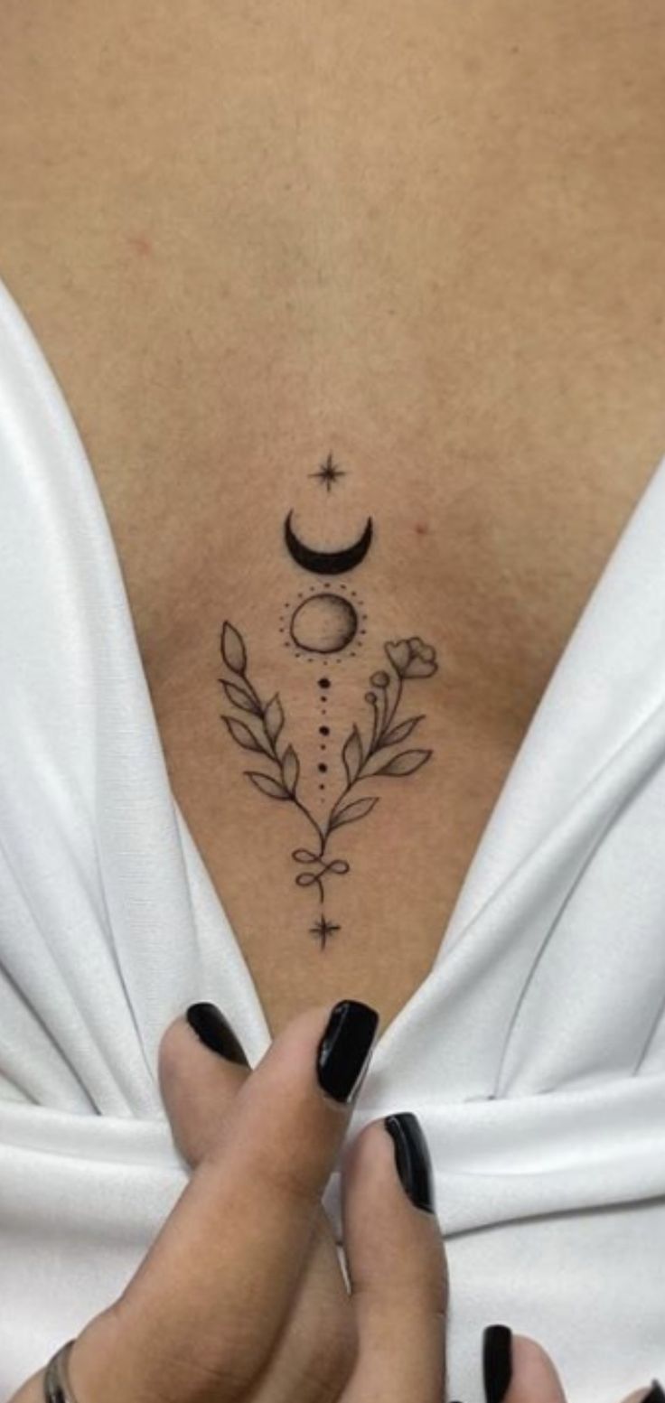 a woman's chest with an arrow and crescent tattoo on her left side ribcage