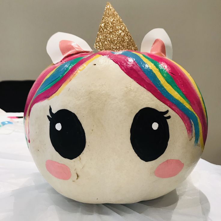 a close up of a painted pumpkin with a unicorn's face on it and a gold glitter horn