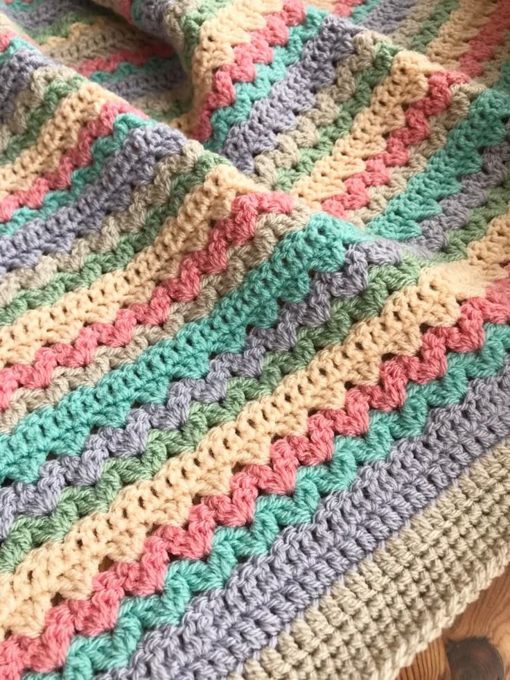 a multicolored crocheted blanket laying on top of a wooden table