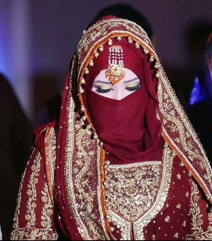 a woman wearing a red veil and headdress with gold jewelry on her face