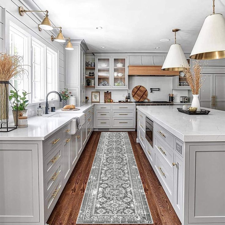 a large kitchen with white cabinets and wooden floors, along with a blue runner rug on the floor