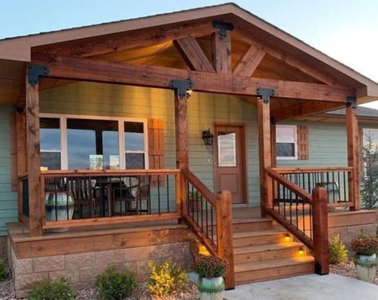 a small house with wooden steps and railings on the front porch, along with potted plants