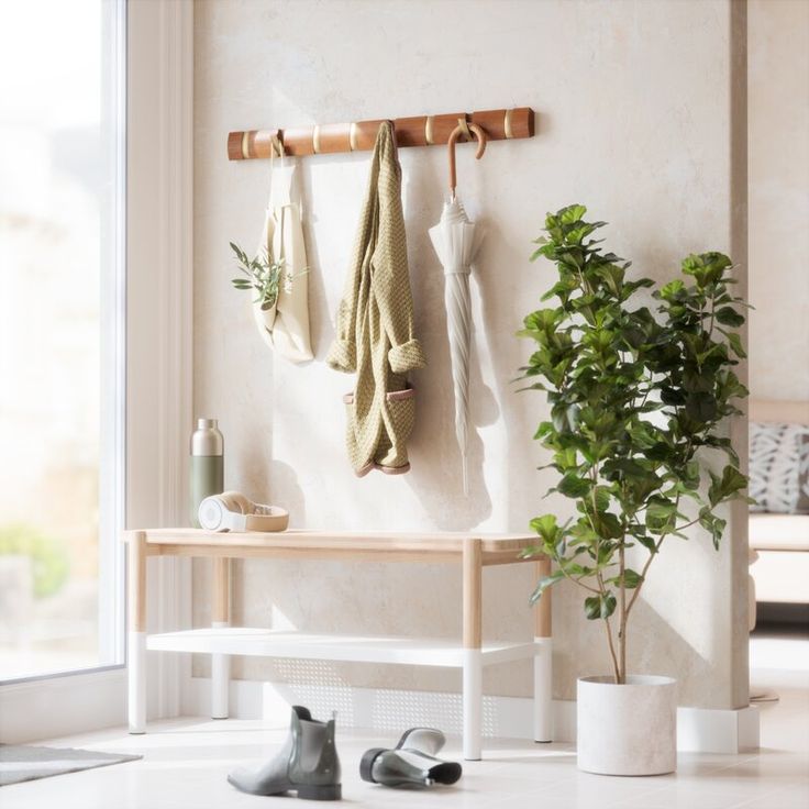 two towels hanging on a rack next to a potted plant and shoes in front of a window