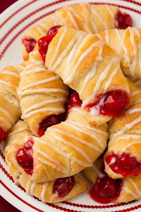 a white plate topped with croissants covered in cream and cherry toppings