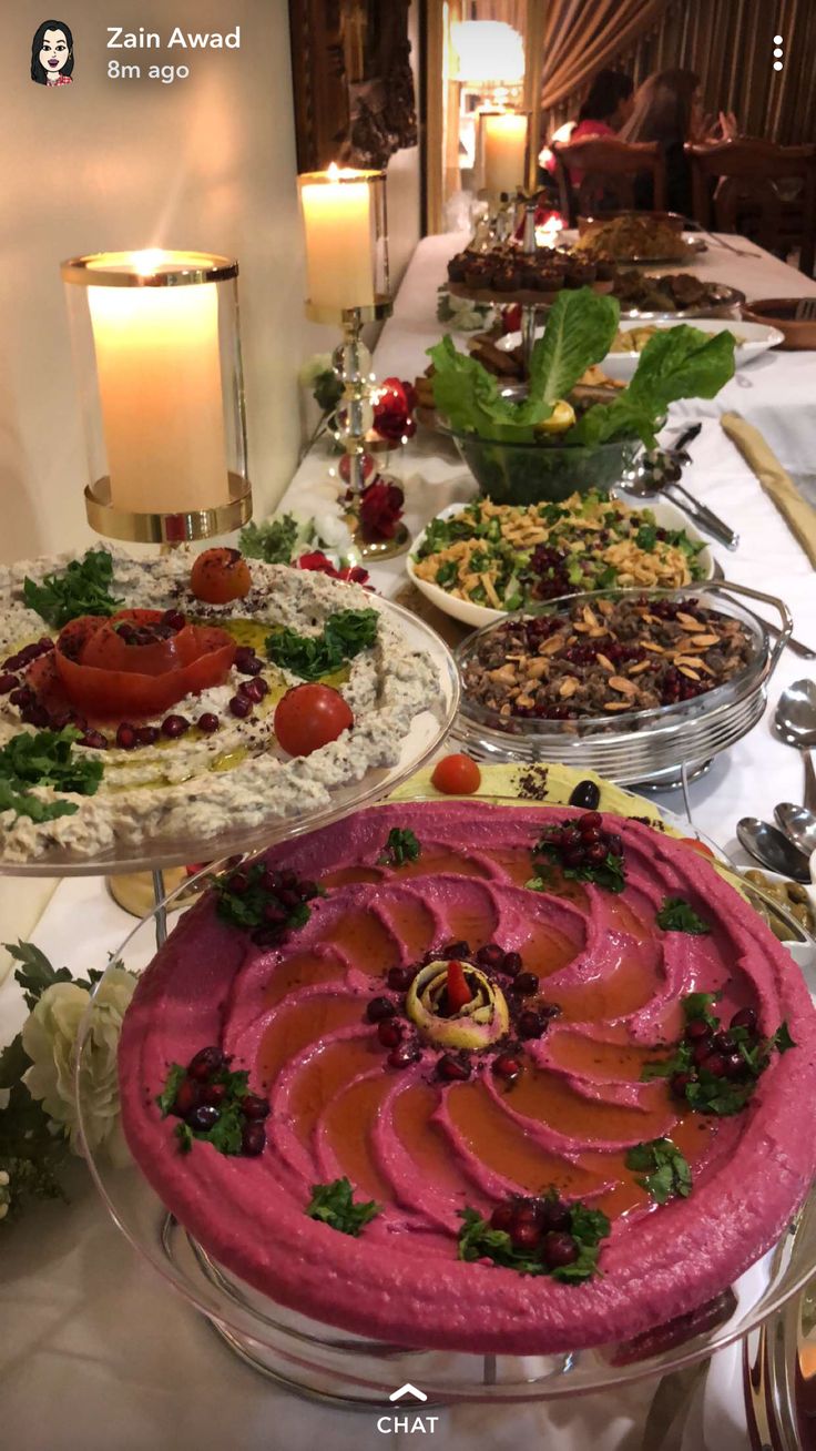 a long table with many different types of food on it and candles in the background