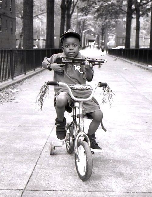 a young boy riding a bike down the street with an object in his mouth and wearing a helmet