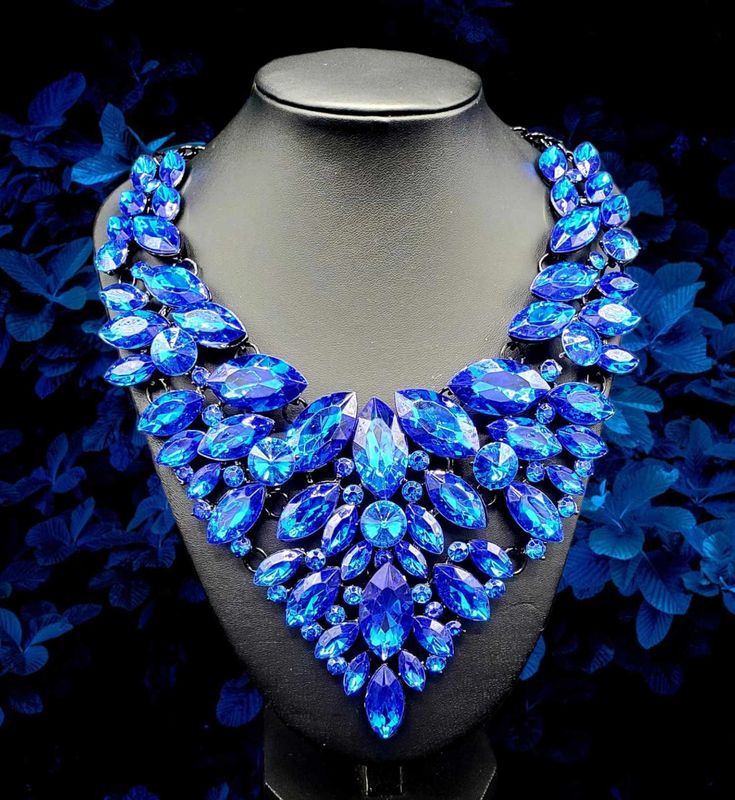 "Blue Paradise": Dare to step into the unknown and explore the depths of fashion and style with the Blue Paradise Necklace. This bold statement necklace will spice up any outfit and help you stand out with its vibrant blue color. Take the plunge and make a statement with this amazing accessory! Blue stone bib has multiple hinges which allows this necklace to move with the body. Approximately 21" with extender. Blue stone adorned bib measures about 7" long! Sapphire Crystal Necklaces For Party, Sapphire Crystal Necklace For Party, Elegant Blue Bib Necklace For Party, Party Turquoise Crystal Necklaces, Blue Crystal Necklaces For Party, Blue Choker Jewelry For Party, Blue Crystal Rhinestone Necklace For Party, Blue Rhinestone Necklace For Party, Blue Party Choker Jewelry