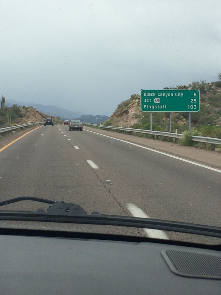 a car driving down the highway with two green signs on it's back end