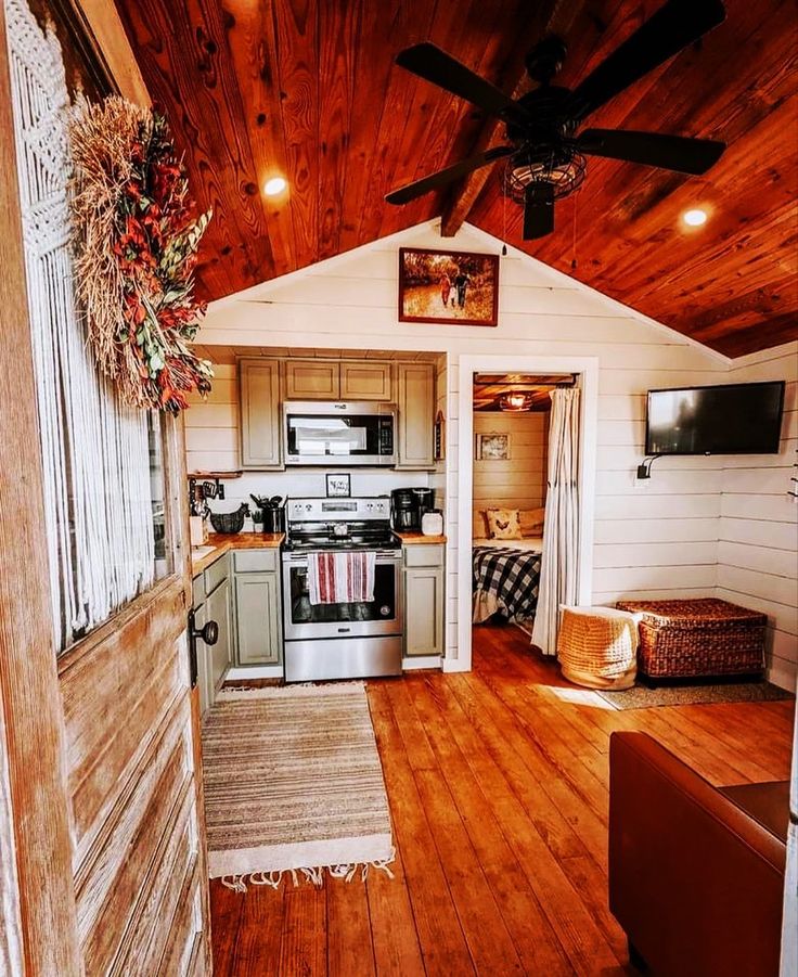 an open kitchen and living room with wood flooring in a small cabin style home