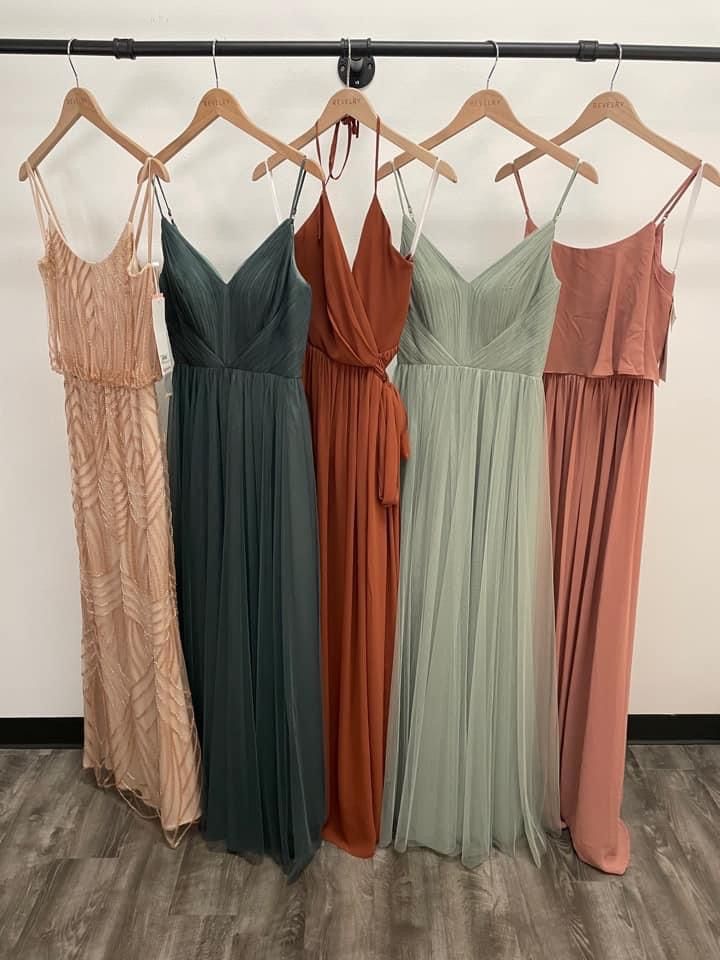 four dresses hanging on a rack in front of a wall