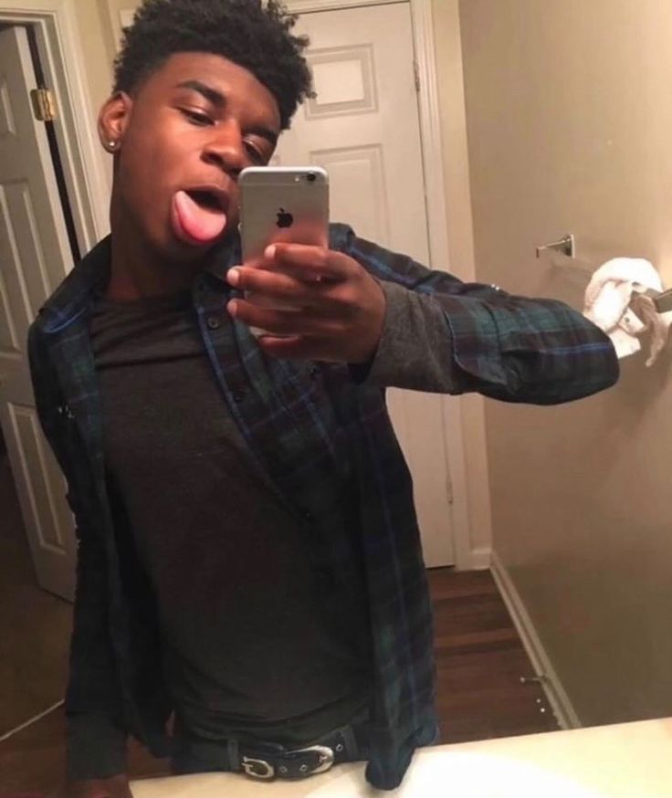 a man taking a selfie with his cell phone in front of him and sticking out his tongue