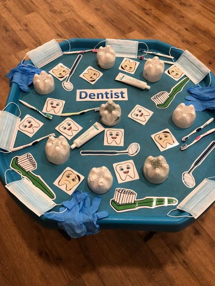 a blue tray topped with dental instruments and toothbrushes on top of a wooden floor