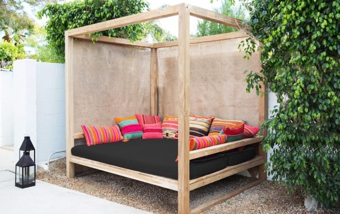 a bed sitting in the middle of a yard with pillows on it's sides