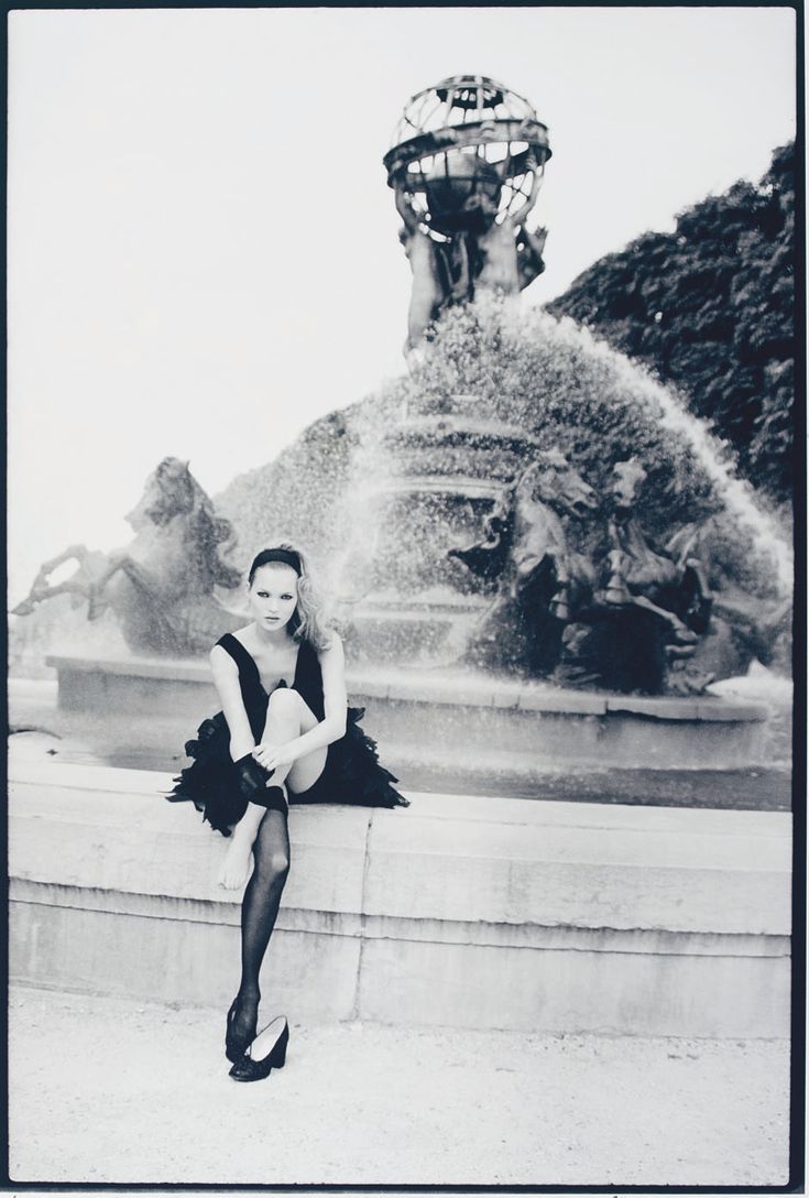 a woman sitting on the edge of a fountain