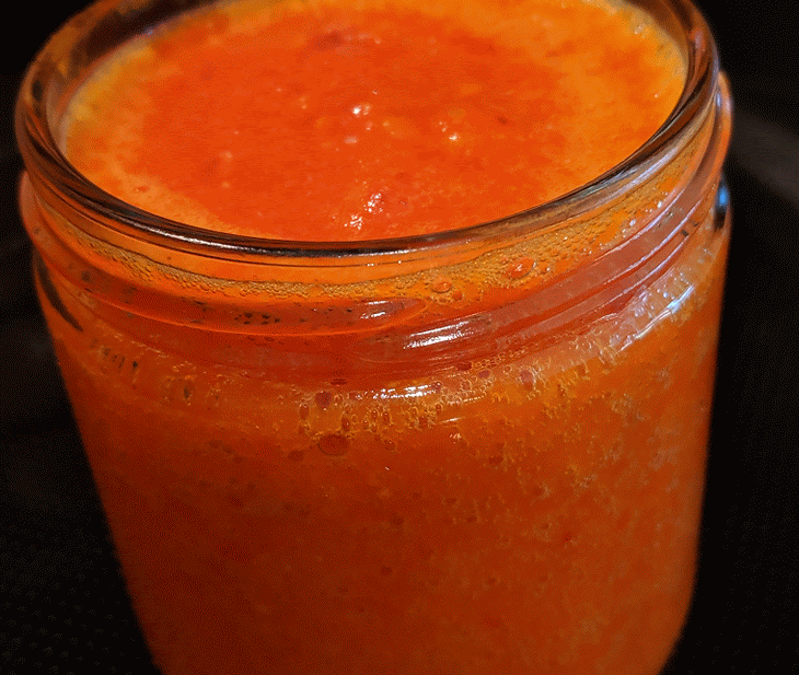 a jar filled with orange liquid sitting on top of a black cloth covered tablecloth