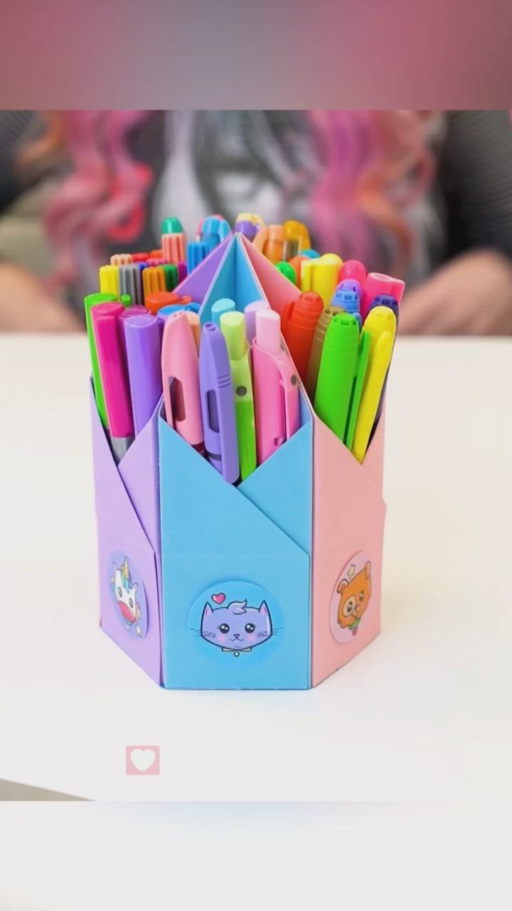 This may contain: a cup filled with lots of colorful pens and pencils on top of a table