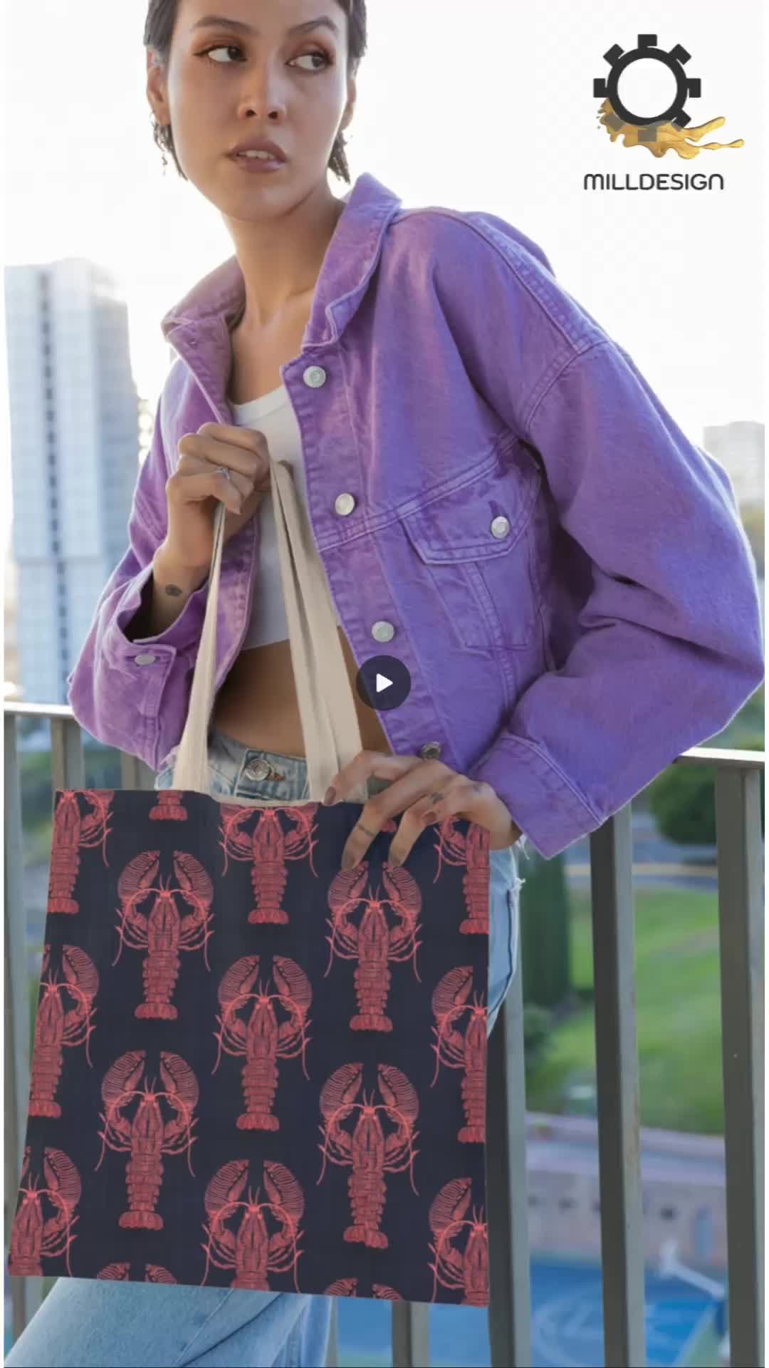 This may contain: a woman holding a shopping bag with lobsters on it and the words milldesign