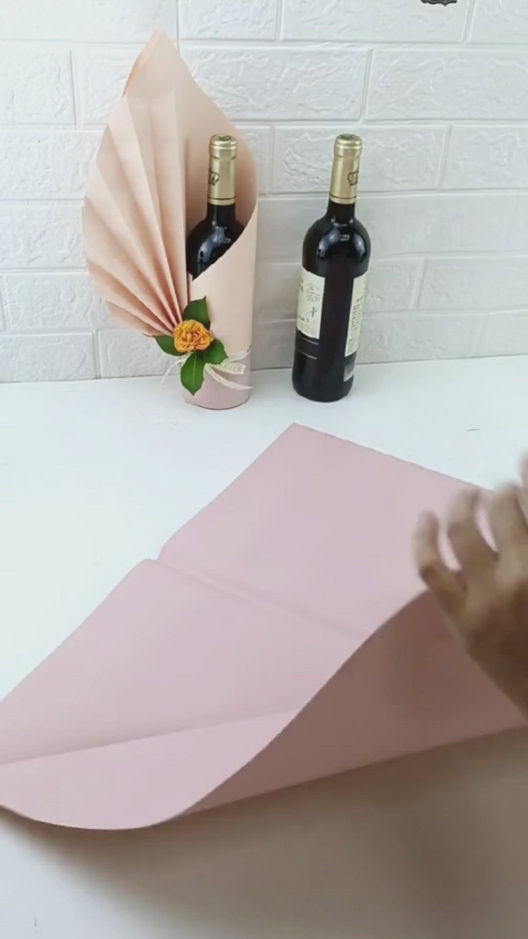 This may contain: a pink origami paper boat sitting on top of a table next to two bottles of wine