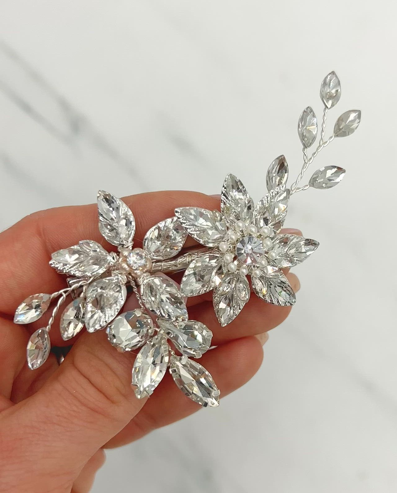 This may contain: a person holding a crystal flower brooch in their hand