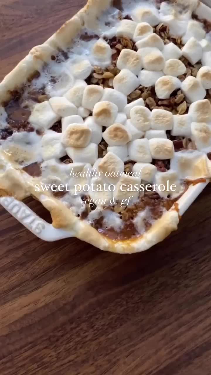 This may contain: a dessert with bananas and marshmallows in it on top of a wooden table