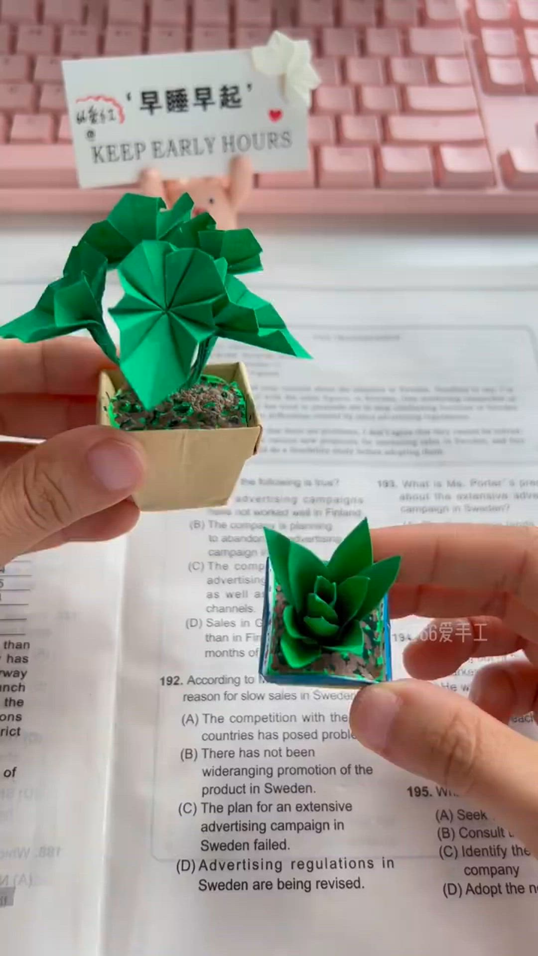 This may contain: a person is holding a small plant in their left hand and reading a book on the desk