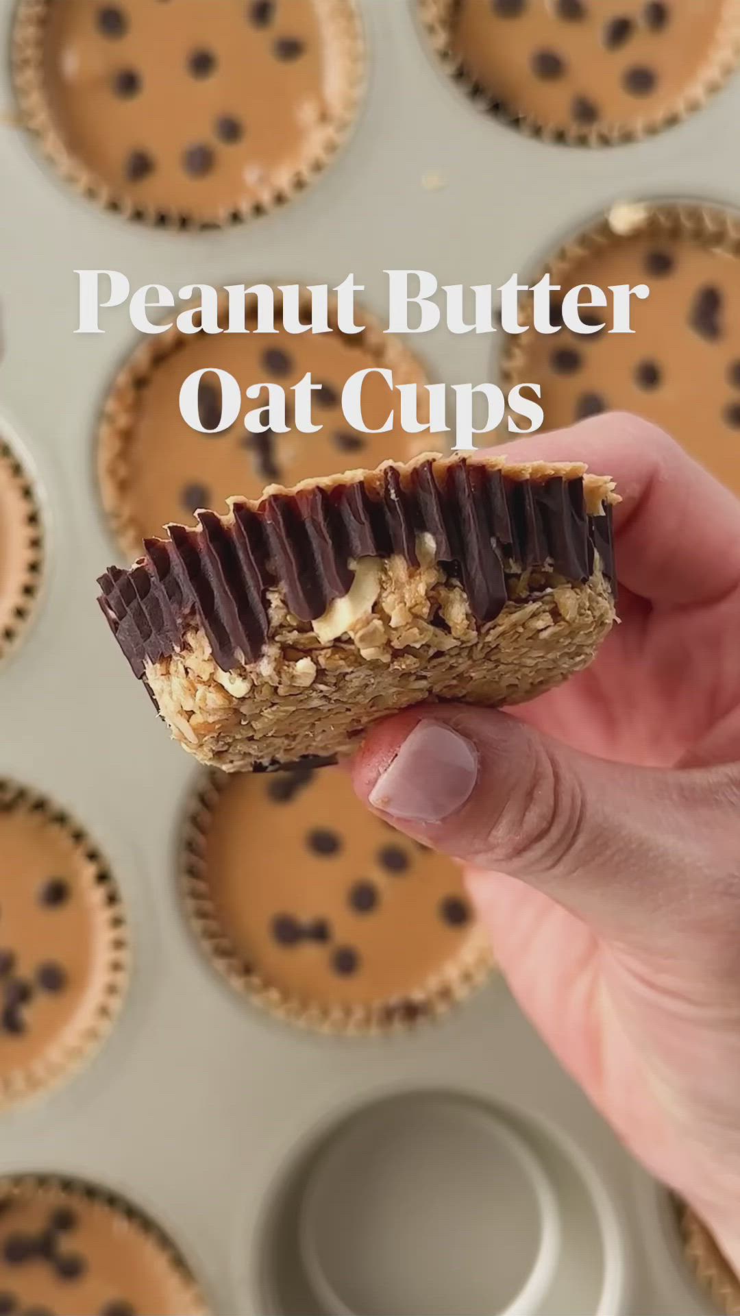 This may contain: two hands holding a cupcake in front of a muffin tin filled with chocolate chips