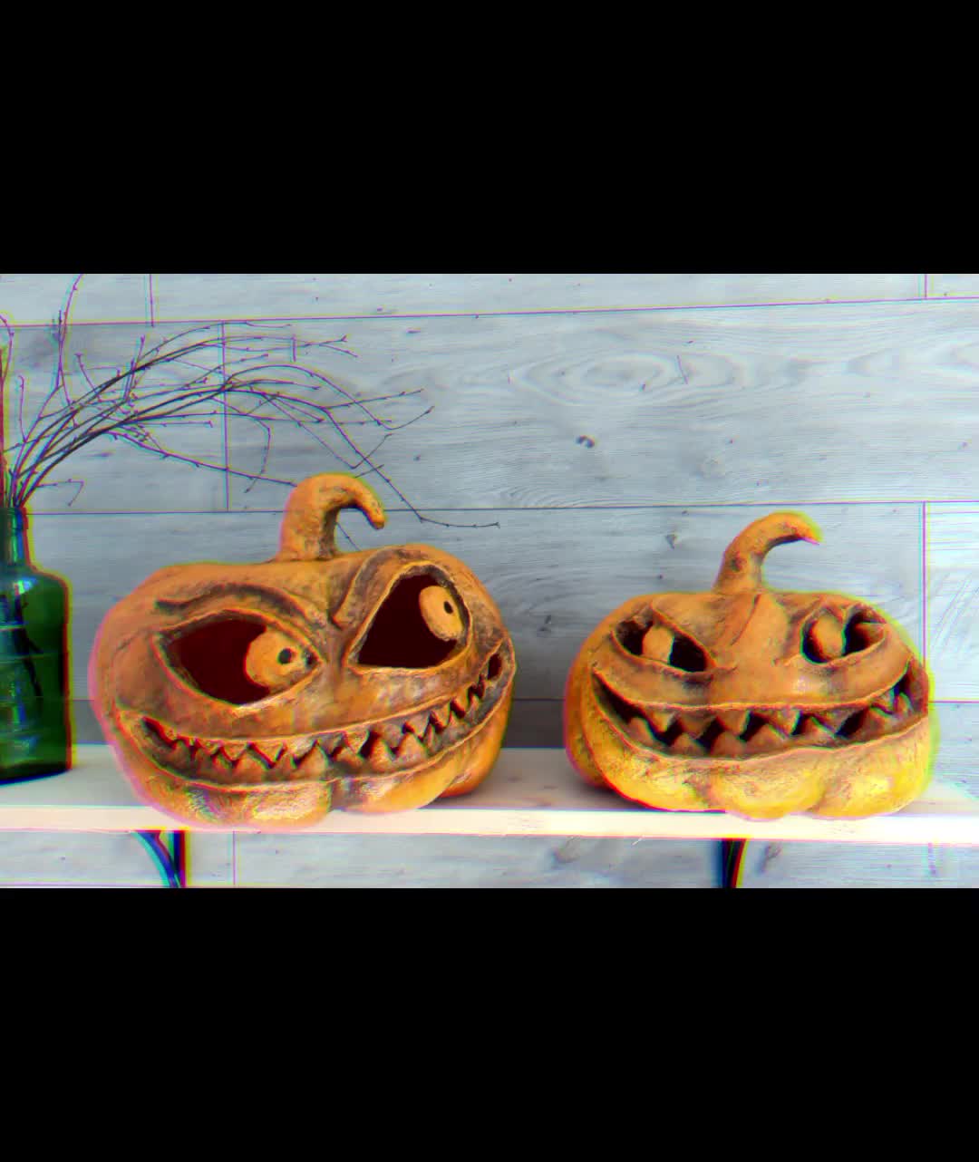 This may contain: two carved pumpkins sitting on top of a shelf next to a bottle and vase