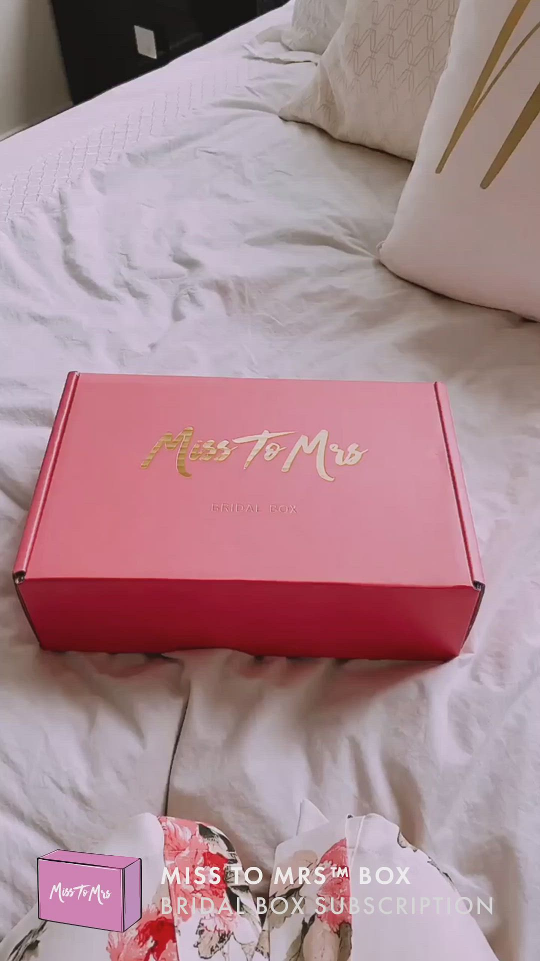 This may contain: a pink box sitting on top of a white bed next to pillows and pillow cases