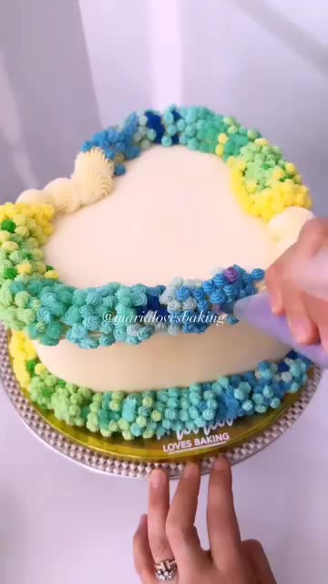 This may contain: someone is decorating a cake with blue, yellow and green icing