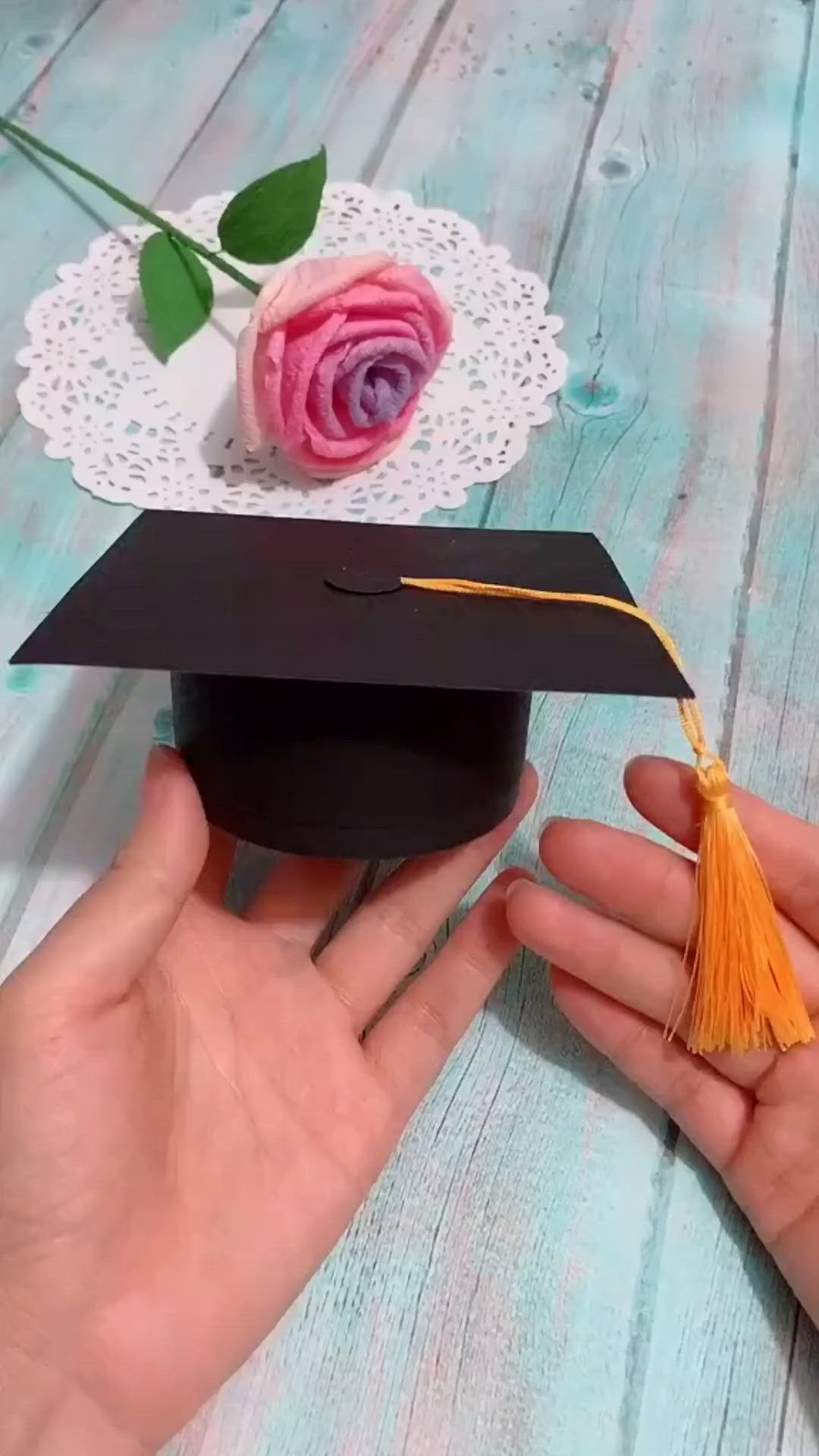 This may contain: someone is holding a graduation cap with a rose on it