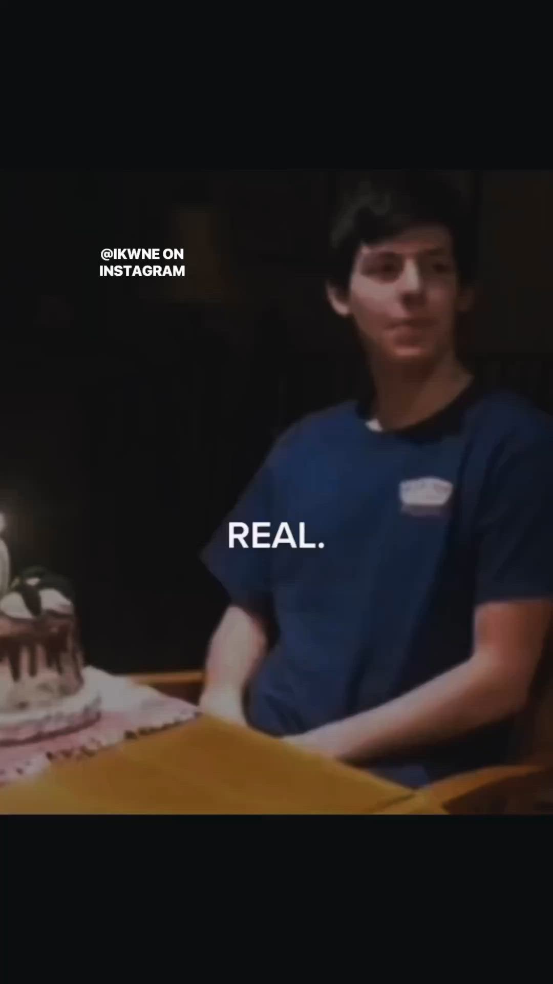 This may contain: a young man sitting in front of a cake with candles on it that reads real