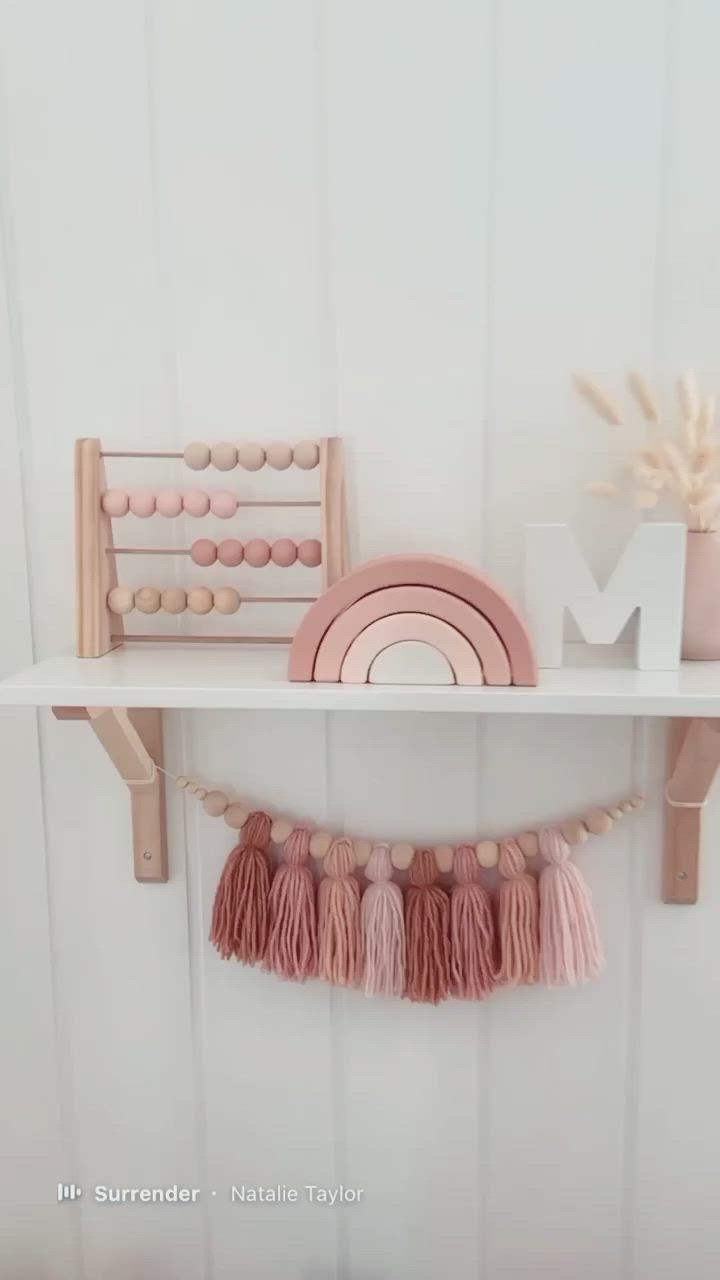 This may contain: a shelf that has some items on it and is decorated with pink tassels