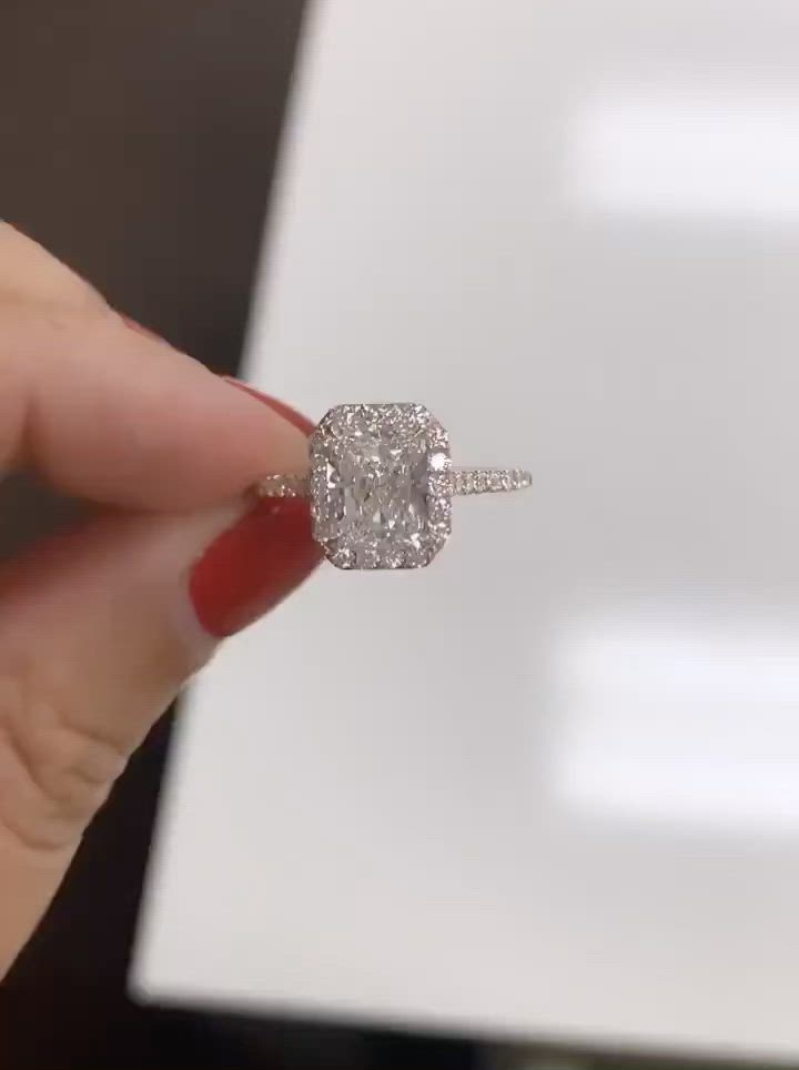 This may contain: a woman's hand holding an engagement ring in front of a white box with a diamond on it