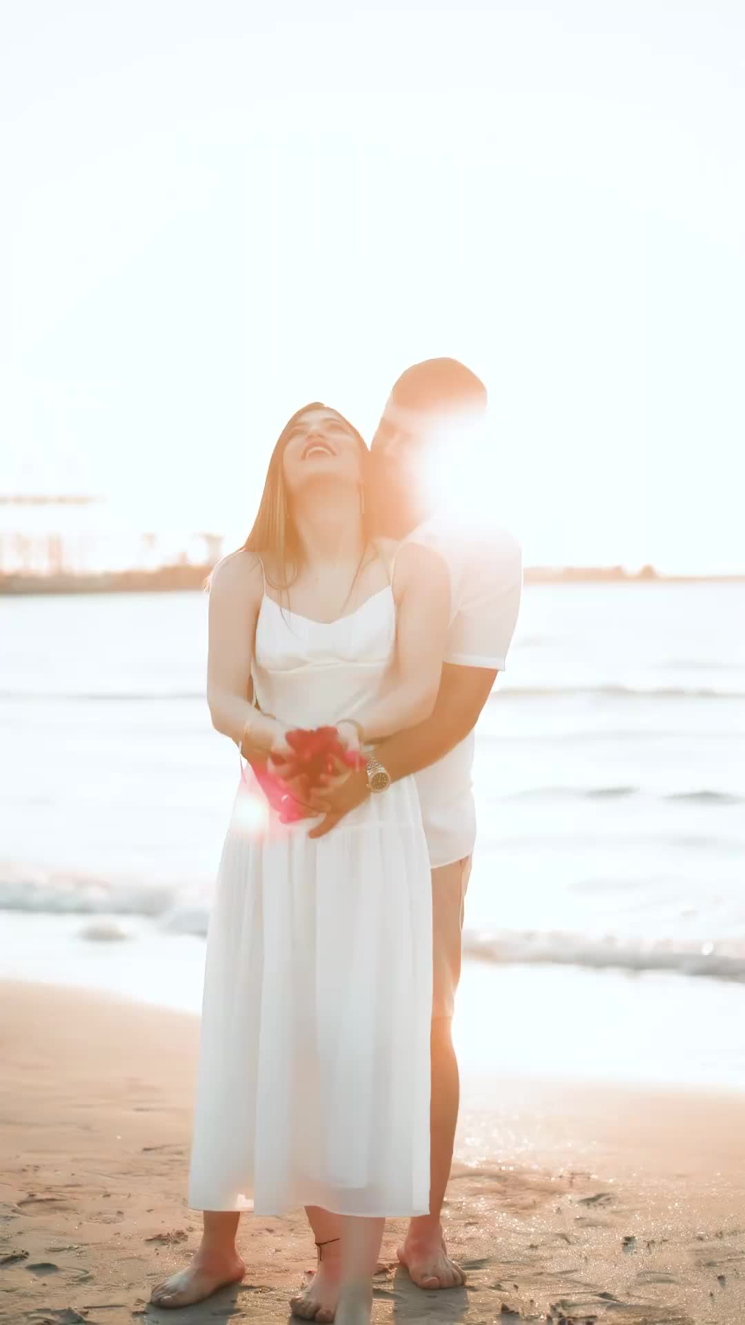 This may contain: a man and woman standing next to each other on a beach