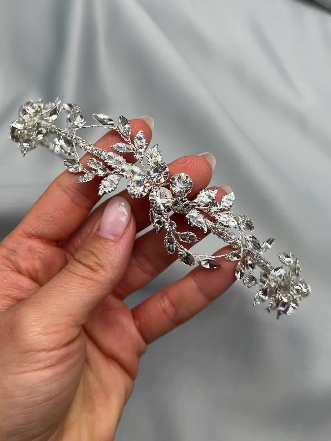 This may contain: a hand holding a crystal flower hair comb