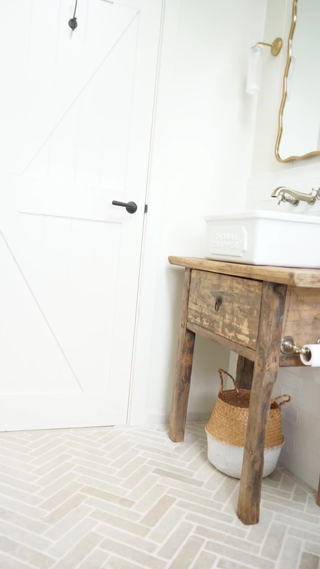 This may contain: a bathroom with a sink, mirror and wooden table in the middle of the room