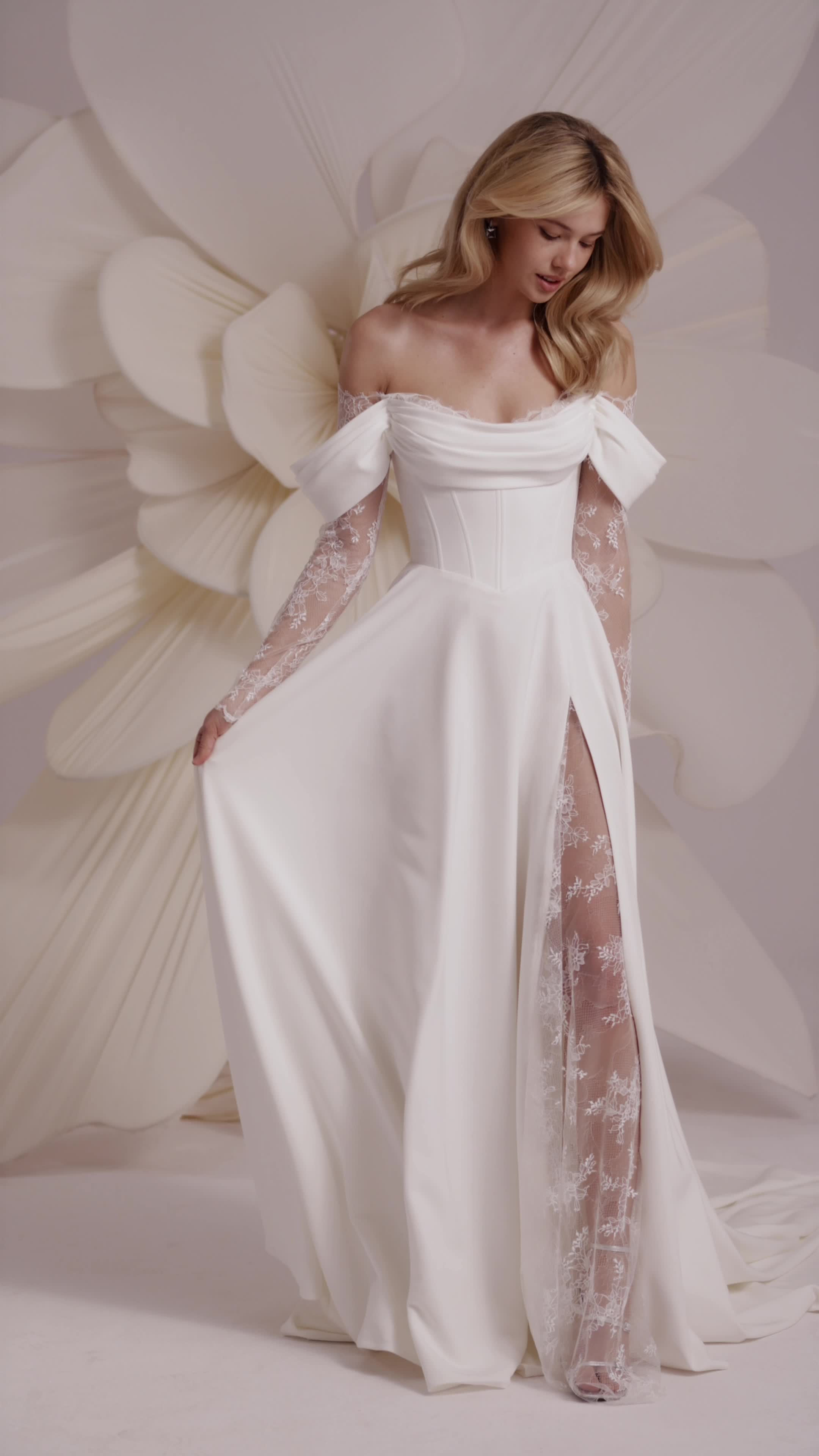 This contains: a line wedding dress with off the shoulder sleeves and slit