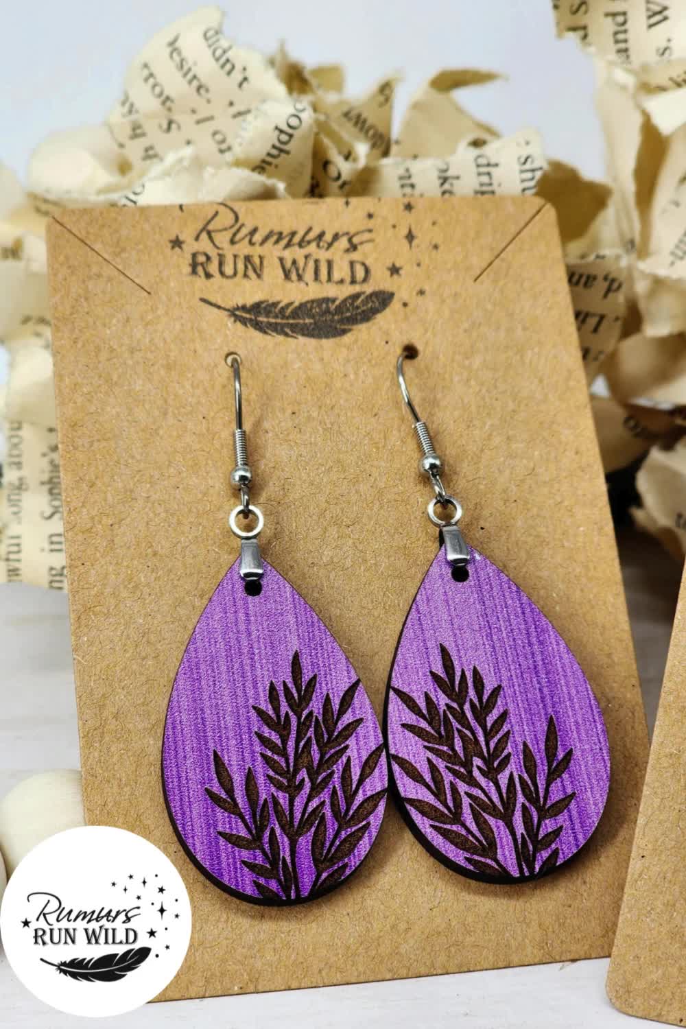 This may contain: two wooden earrings with purple leaves on them