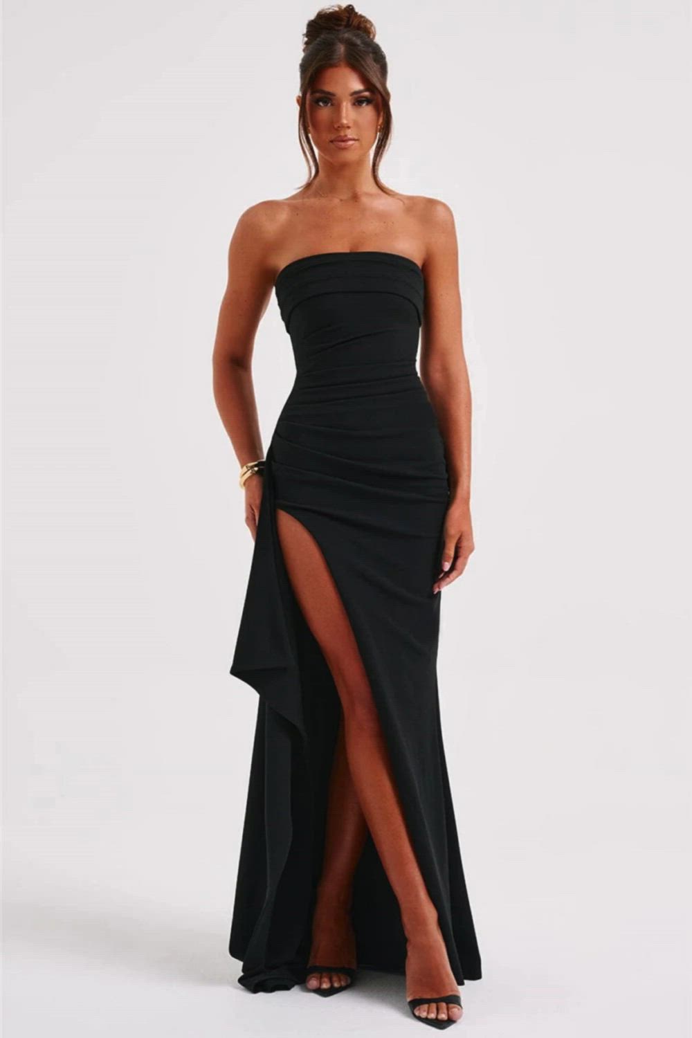 This contains: This Strapless Backless High Split Maxi Dress is perfect for any night out with its sleek black design and bodycon fit. The dress features an off-shoulder neckline and sleeveless style, highlighting your shoulders and arms. The high split adds a touch of flirtiness, while the stretchy fabric ensures a comfortable fit. Elevate your club party look with this chic and versatile dress.