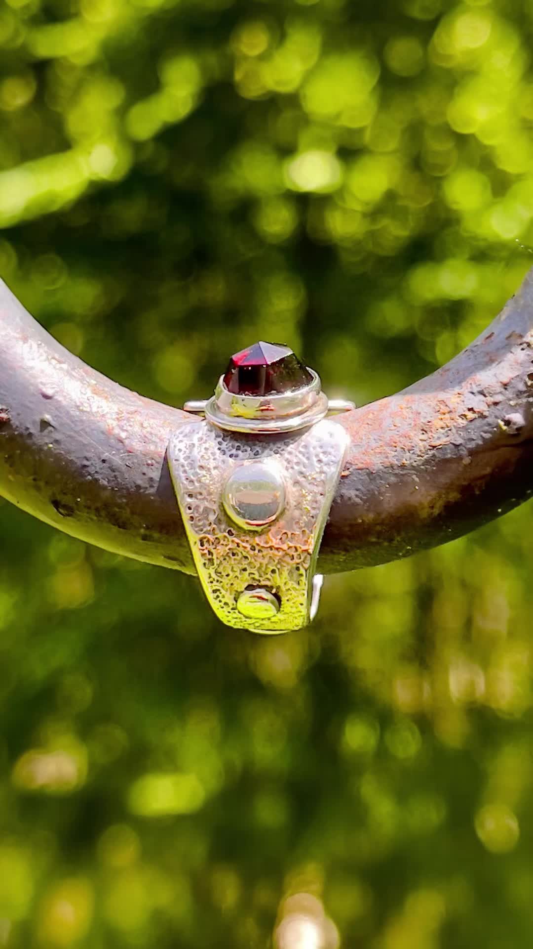 This may contain: a close up of a metal object with water droplets on it and trees in the background