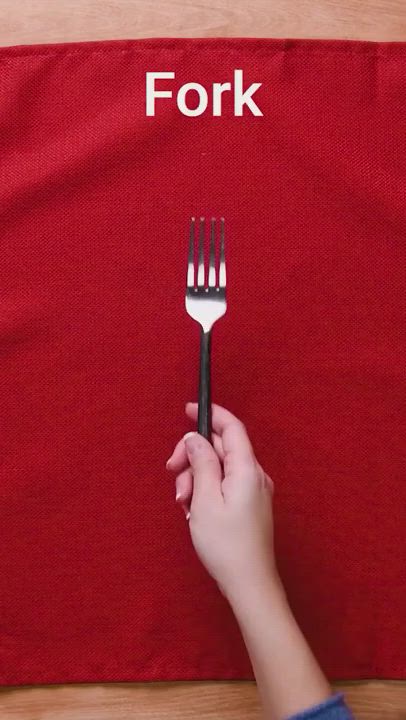 This may contain: a person holding a fork in front of a red cloth with the word fork written on it