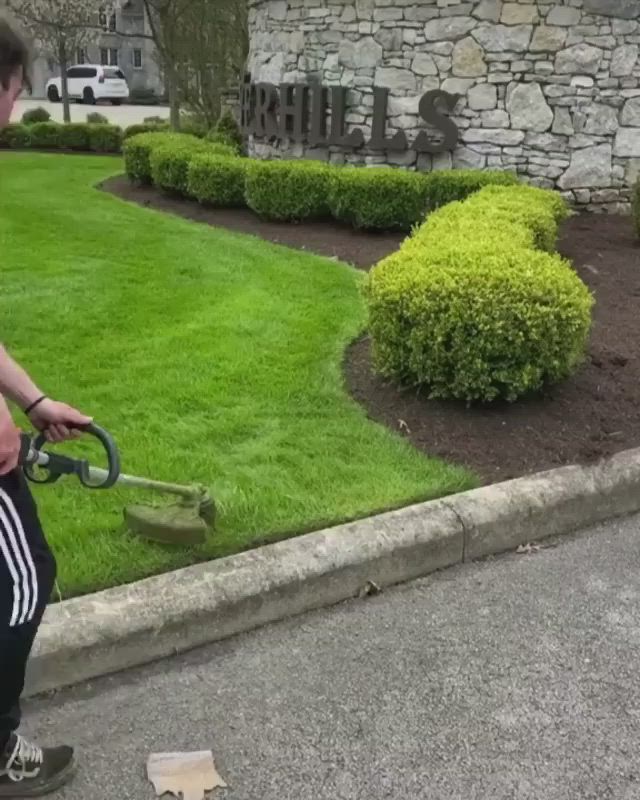 This may contain: a man is using a lawn mower to cut the grass in front of his house